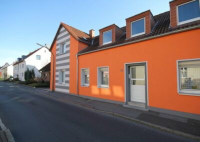Haus mit orangener Farbe und weiß-grauen Streifen Farbe an einer Stelle