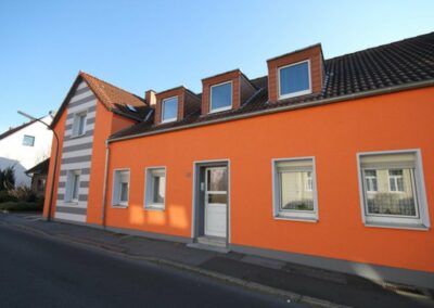 Haus mit orangener Farbe und weiß-grauen Streifen Farbe an einer Stelle