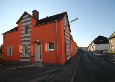 Haus mit orangener Farbe und weiß-grauen Streifen Farbe an einer Stelle