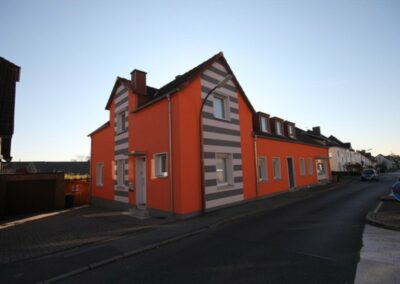 Haus mit orangener Farbe und weiß-grauen Streifen Farbe an einer Stelle
