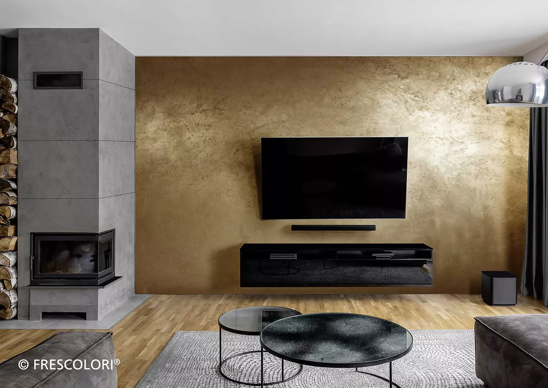 Wohnzimmer mit Kamin und Fernseher der an Wand in Echtmetall Design befestigt ist